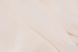 Nahaufnahme von leichtem cremefarbenem Netzstoff mit feiner Textur und elegantem Fall.