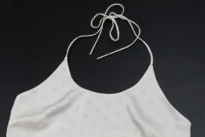 Close-up detail of a white polka dot halter top showing the tie neck and soft fabric texture