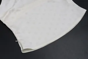 Detail view showing white tonal polka dot fabric texture and side zipper of skirt