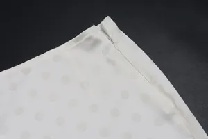 Close-up detail of white polka dot skirt showing the invisible side zipper and fabric texture