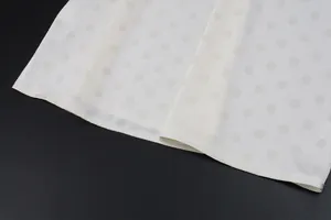Close-up detail of white polka dot fabric hemline showing premium textile texture