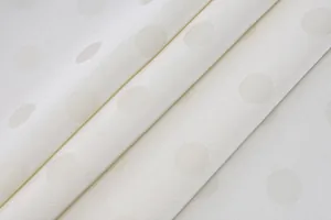 Macro detail of white jacquard fabric with elegant tonal polka dot pattern for women