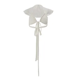 Detailed view of the white lace cropped top featuring shell accents and tie-front closure.
