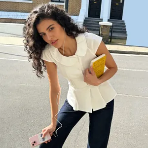 Detalle de un top blanco ajustado con un elegante cuello redondo lucido por una modelo en la calle
