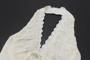 Dettaglio di un top a fascia in pizzo bianco crema con scollo a V e ricami fiori