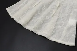 Dettaglio della trama del pizzo floreale bianco di questa canotta estiva da donna