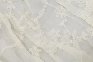 Dettaglio ravvicinato del tessuto in pizzo floreale con ricami bianchi eleganti