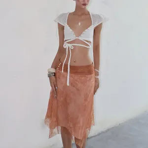Detail view of a white lace flutter sleeve crop top with shell accents and waist ties.