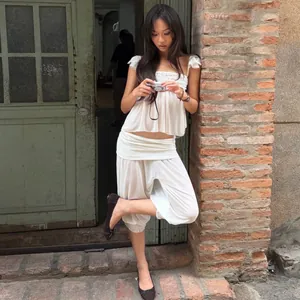 Model draagt een Franse witte ruches top en lantaarn broek set in een rustieke omgeving