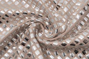 Close-up detail shot of silver metallic grid pattern on nude knit fabric material.