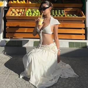 Asian model wearing a white crochet top and long flowy skirt posing at a fruit stall