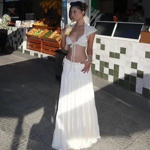 Outdoor lifestyle shot of a white crochet crop top with tie-front and cap sleeves detail