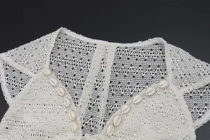 Detailed macro shot of white crochet lace top featuring seashell neckline accents
