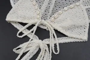 Close-up of white crochet crop top with seashell decorations and delicate tie strings.