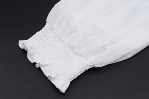 Detailopname van witte doorschijnende mesh mouw met elegante gesmokte elastische manchet