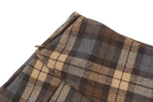 Close-up detail showing the concealed side zipper and wool-like plaid texture of the pleated skirt