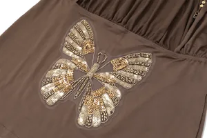 Close-up of golden sequin butterfly embroidery on brown dress fabric detail view