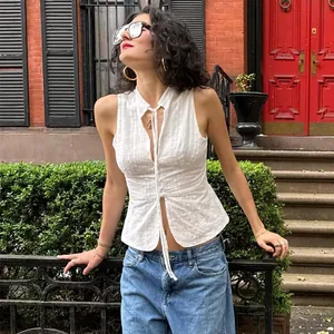 Detail view of a white sleeveless tie-front cropped top in a street style setting