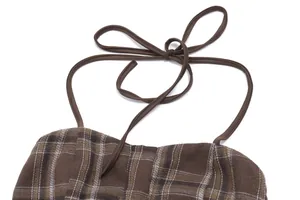 Primer plano detallado del lazo de cuello halter a cuadros marrones de un top de verano retro.