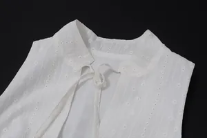 Close-up detail of white sleeveless crop top featuring delicate eyelet lace and front tie-up