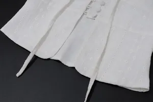 Detailed macro view of white embroidery and tie-front closure on a sleeveless vest