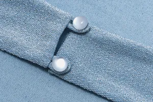Macro detail of shimmering blue fabric texture and elegant pearlescent button closure