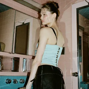Back view detail of a mint green lace-up camisole in a vintage pink bathroom setting