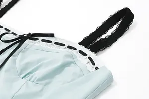 Close-up detail of light blue camisole featuring white lace trim and black ribbon bow