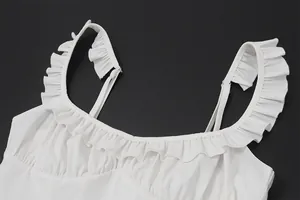 Detailed view of a white low-cut dress with ruffled straps and pleated neckline detail