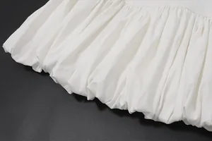 Close-up view showing the intricate pleated texture and bubble hem of a white dress