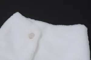 Close-up of luxury white faux fur shawl featuring an elegant pearl-encrusted button