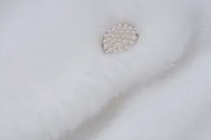 Close-up of exquisite pearl-encrusted button on soft white faux fur plush shawl detail