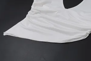Detailed view of the white irregular hem and ruched side of a sexy halter neck top.