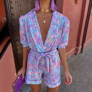 Vibrant abstract print short sleeve V-neck belted romper for summer resort fashion.