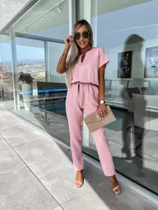 Dettaglio di elegante tuta rosa a maniche corte con scollo a V e raffinato tubo di rame decorato