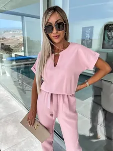 Elegante tuta rosa con scollo a V, maniche corte e cintura indossata da una modella