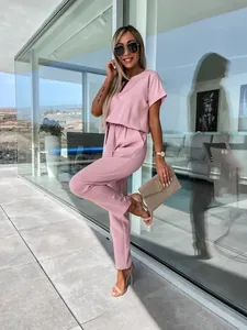 Elegante tuta rosa con scollo a V e maniche corte con cintura decorativa in un contesto moderno