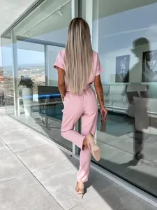 Vista posteriore di un'elegante tuta rosa con scollo a V, maniche corte e cintura