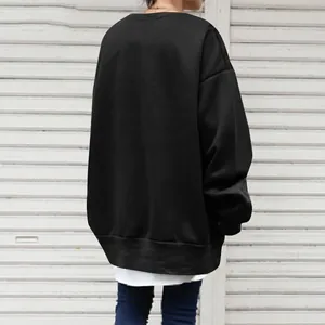 Back view of a loose black crewneck sweatshirt for women in a street style setting