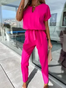 Elegante tuta fucsia con scollo a V, finiture in metallo e una sottile cintura in vita