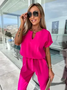 Elegante tuta magenta con scollo a V, dettaglio in metallo dorato e cintura in vita