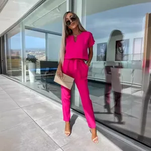 Moderna tuta intera fucsia con scollo a V, maniche corte e cintura in vita indossata dal modello