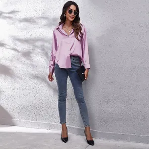 Ganzkörperansicht eines Models in einem lila Satin-Langarmhemd und blauen Skinny Jeans.