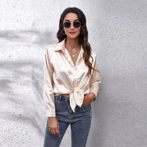 Nahaufnahme einer eleganten champagnerfarbenen Satinbluse mit stilvollem Knotendetail vorne