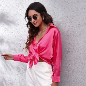Seitenansicht einer leuchtend rosa Satinbluse mit langen Ärmeln und Knotendetail