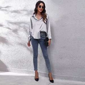 Elegantes silbernes Satin-Langarmhemd kombiniert mit blauen Denim-Jeans an einem Model
