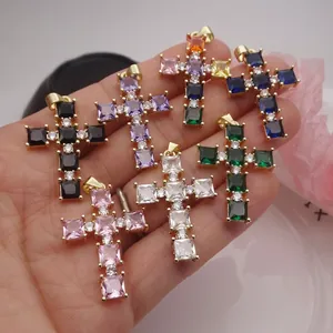 Macro view of various colorful square-cut zircon cross pendants in a hand