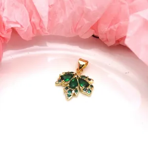 Detailed view of gold copper maple leaf pendant featuring sparkling green zircon stones