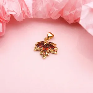 Close-up of gold-plated maple leaf pendant with orange micro-set cubic zirconia stones