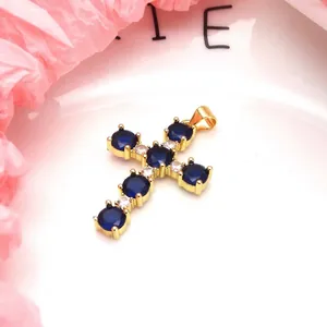 Macro view of a gold-plated cross pendant set with vibrant blue and white zircons.